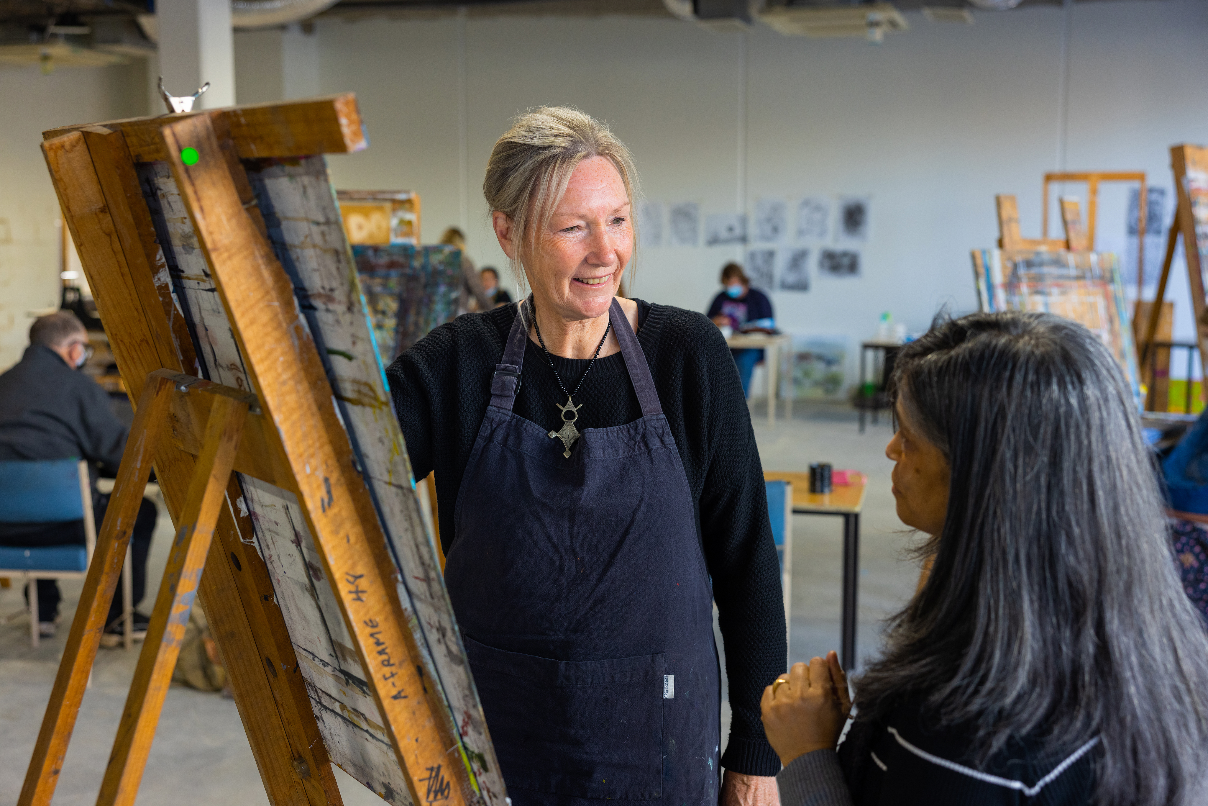 Gillian painting on a canvas discussing her work with a friend